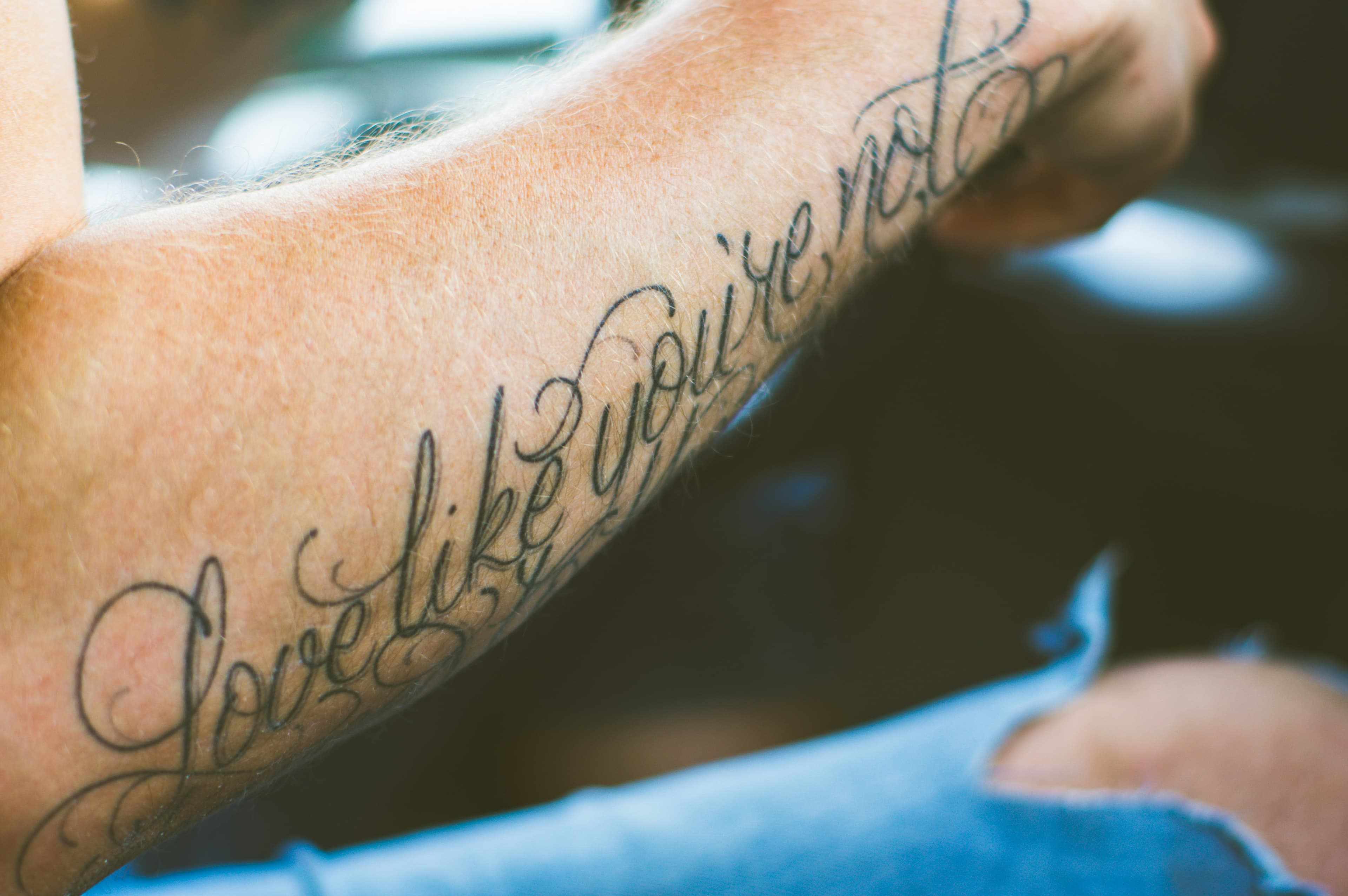 Tatuaje de lettering en cursiva a lo largo del antebrazo