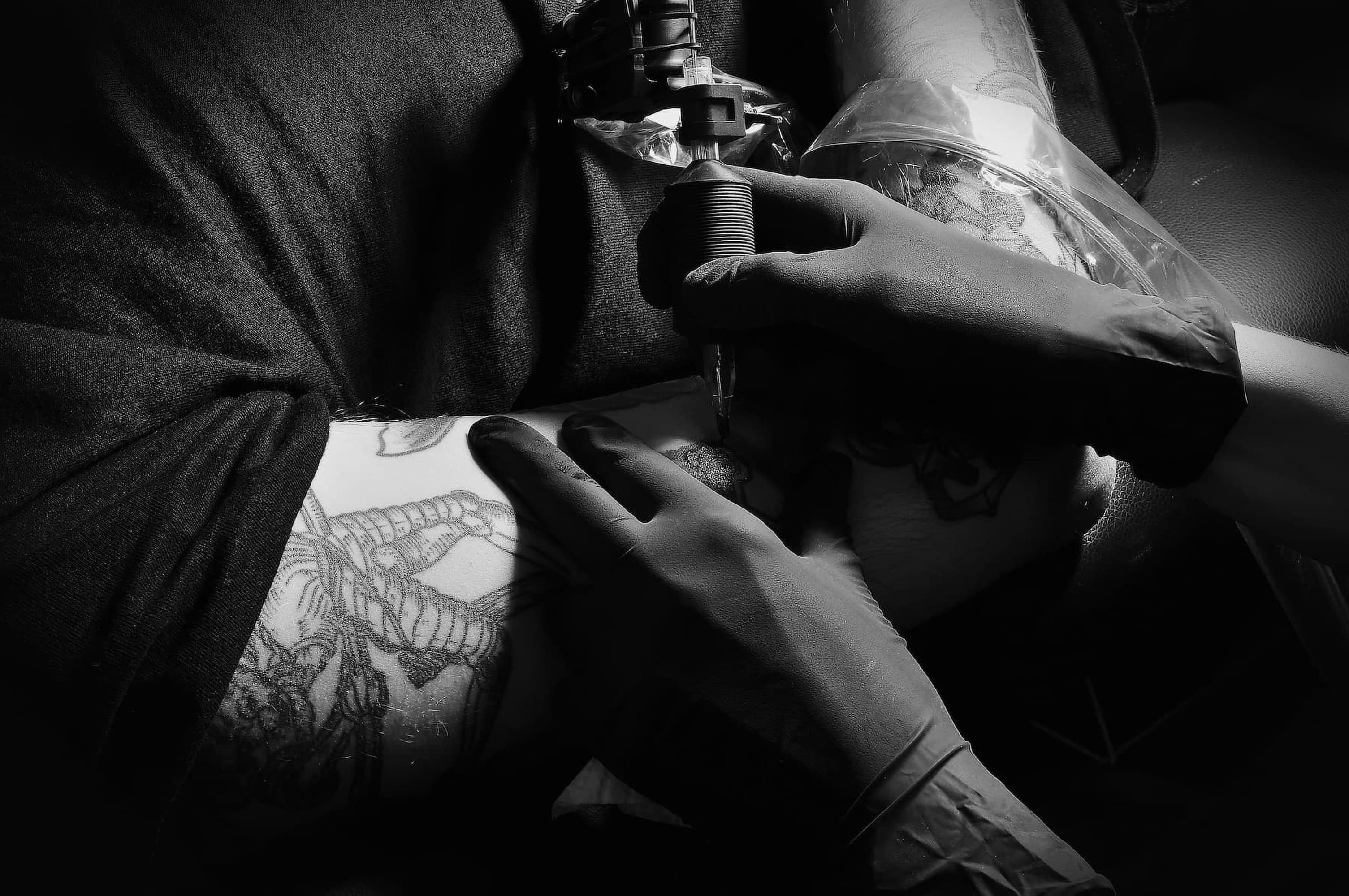 Toma cercana en blanco y negro de manos tatuando