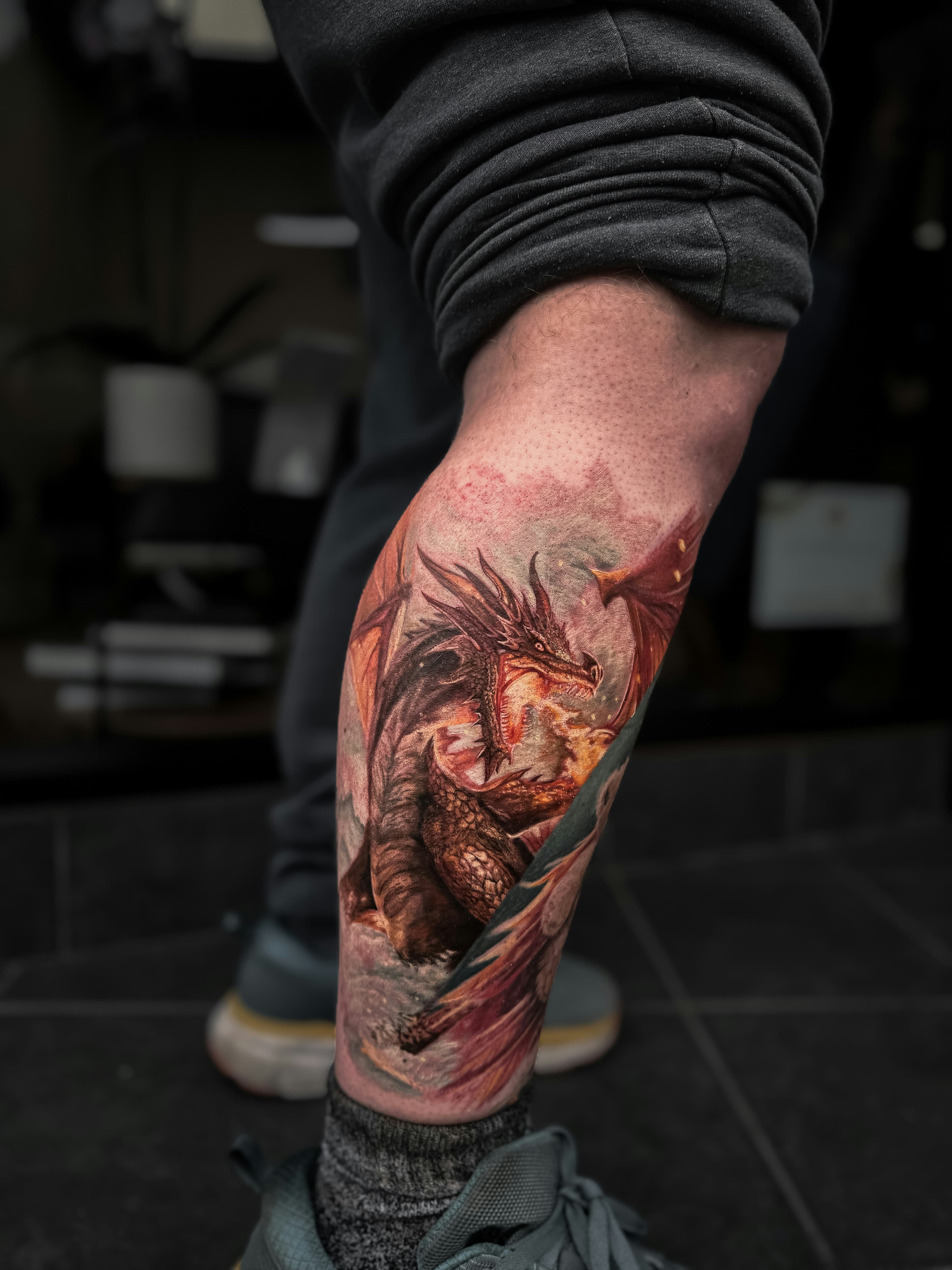 Tatuaje de dragón a color muy vívido recorriendo la pantorrilla
